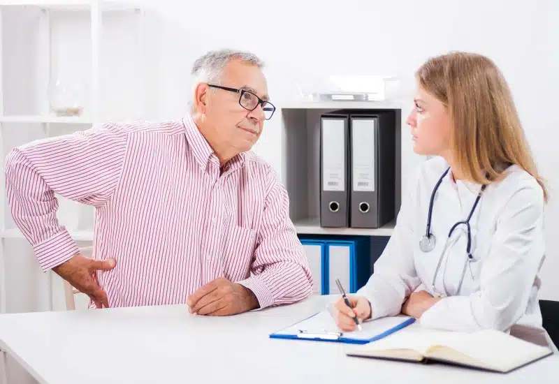 An elderly man explaining his back pains to a doctor