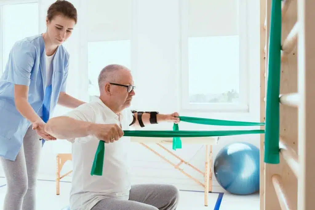 Elderly man doing gymnastic exercises with a young female physio