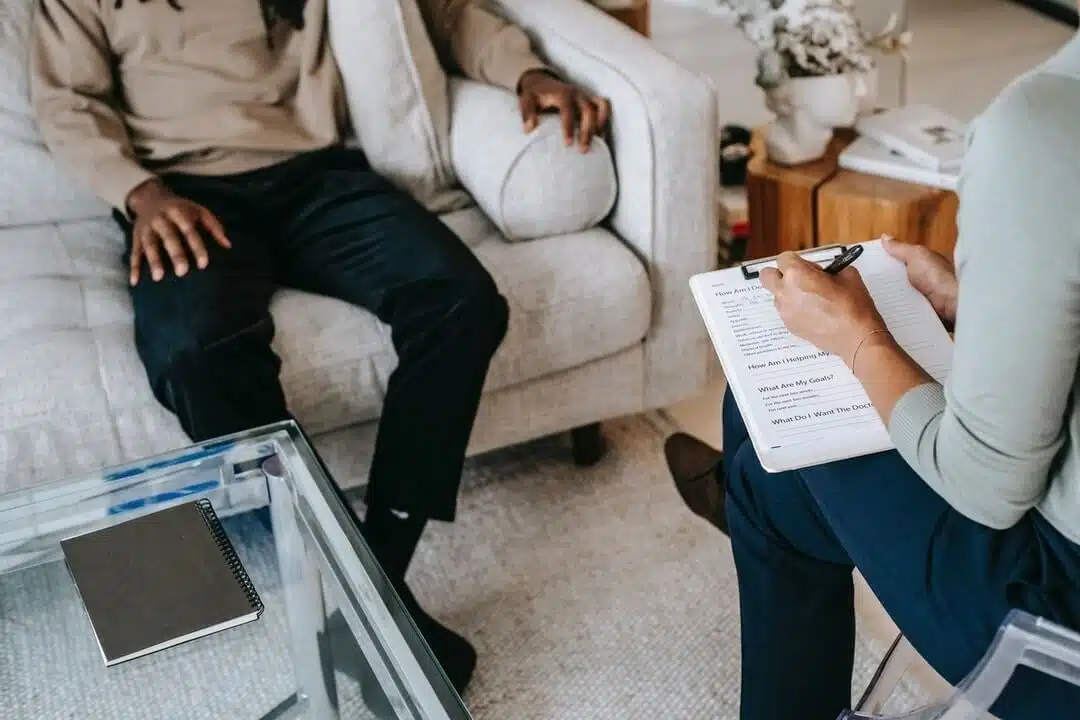 cropped image of doctor writing on a clipboard while talking with a patient during check-up