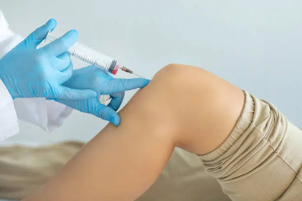 Doctor doing some joint injection on a patient's knee