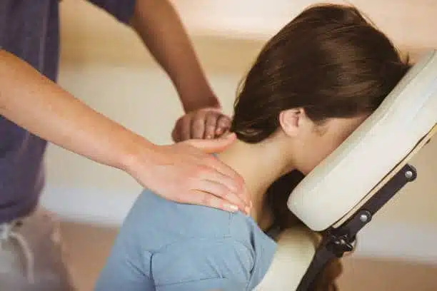 Young woman getting massage in chair in therapy room