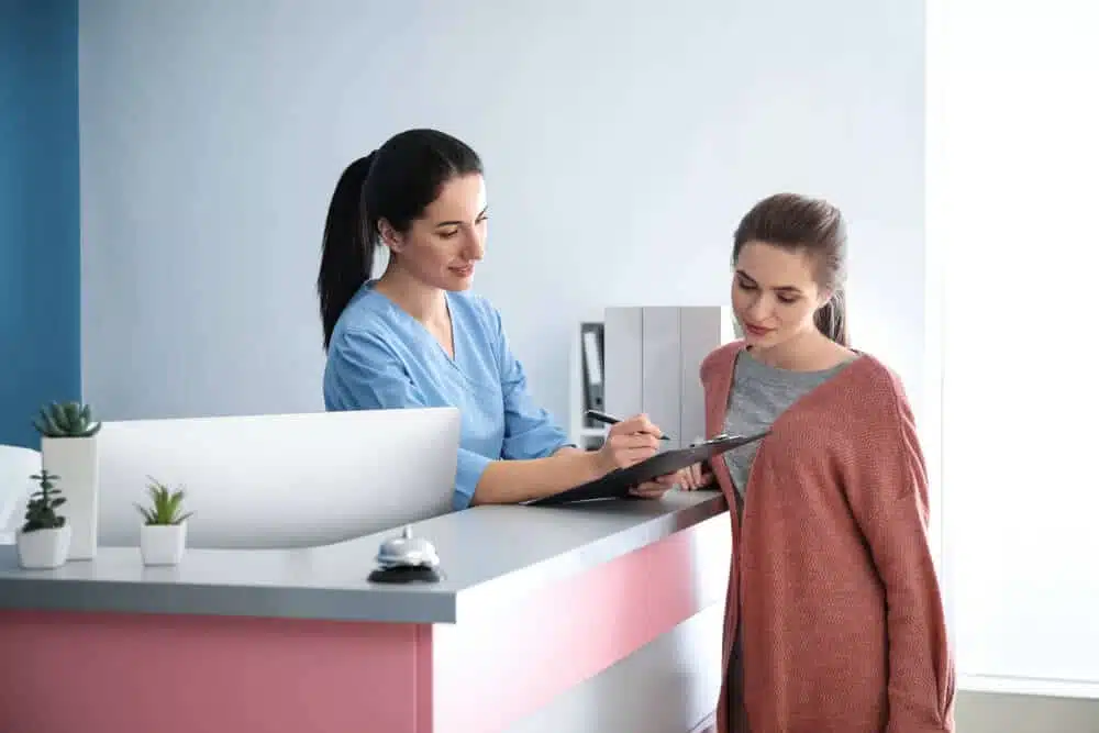 Patient talking to a medical receptionist regarding her health insurance.