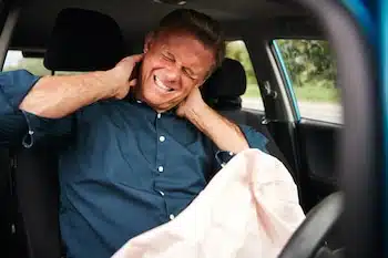 business man holding his neck while inside his car