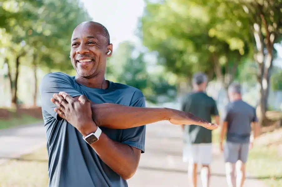 A smiling man stretching in public park