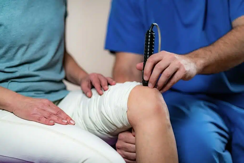 patient's knee getting laser therapy from a therapist