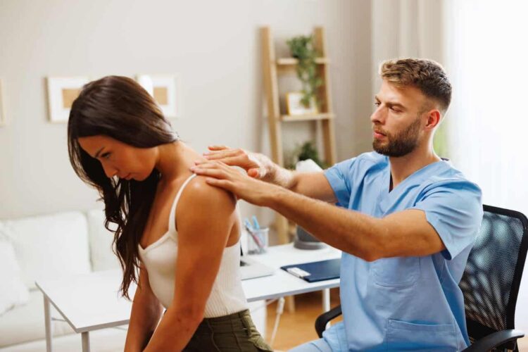 Young woman with neck pain is being examined by a physiatrist